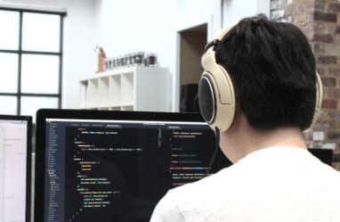 developer with headphones coding at computer