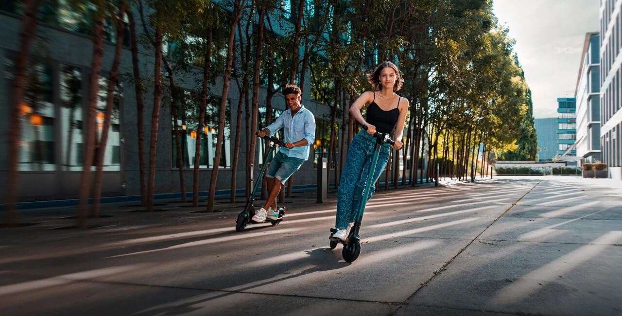 a girl and a boy riding electric scooters in the urban surrounding
